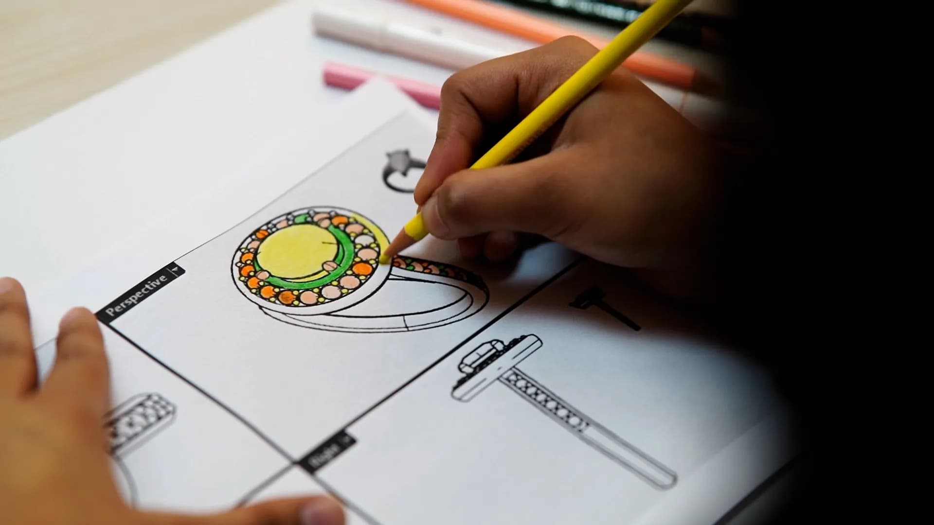 A student rendering a ring design in coloured pencil